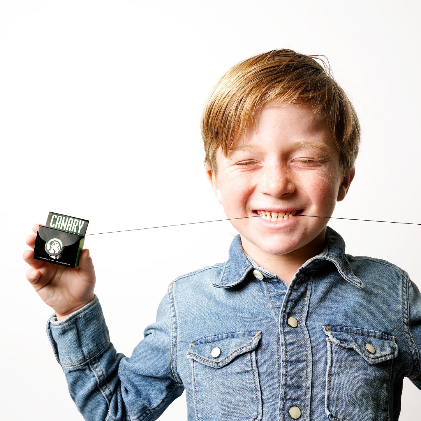 Kid with eyes closed using the Single box of floss, front view. 30m of strong floss. Plastic-free, corn-based PLA.