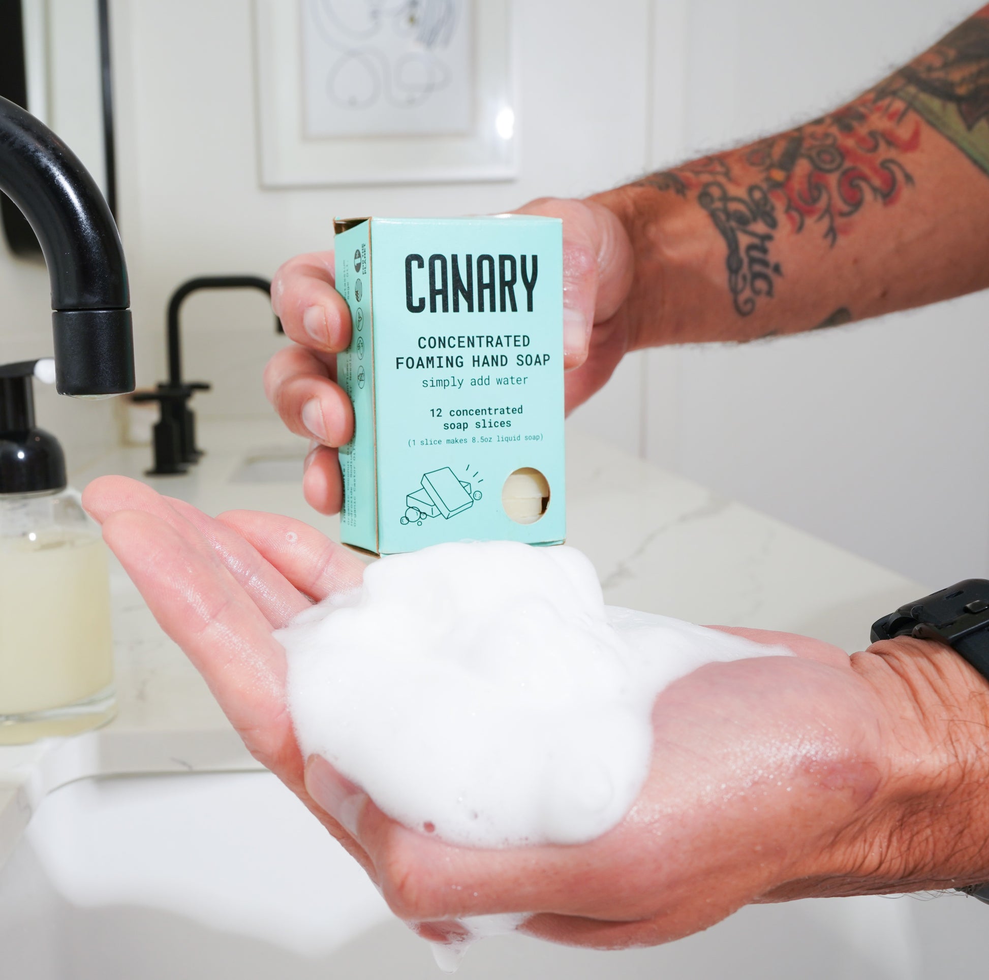 Fir Needle & Sage Concentrated Foaming Hand Soap. Front of the box with hands in sink showing how much foam there is. 12-count box. 